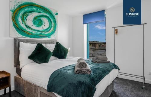 una camera da letto con un letto e asciugamani di THE PENTHOUSE, Spacious, Stunning Views, Foosball Table, 3 Large Rooms, Central Location, River Front, Tay Bridge, V&A, 2 mins to Train Station, City Centre, Lift Access, Parking, WiFi, Mid-Stay Rates Available by SUNRISE SHORT LETS a Dundee