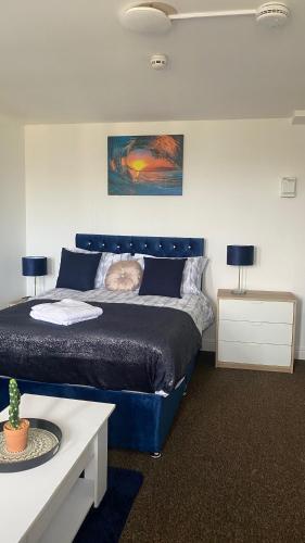 a bedroom with a blue bed and two tables at Bv Cosy Studio Eleven At Deighton Huddersfield in Huddersfield