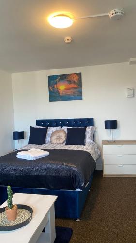Un dormitorio con una cama azul y una mesa en Bv Cosy Studio Eleven At Deighton Huddersfield, en Huddersfield