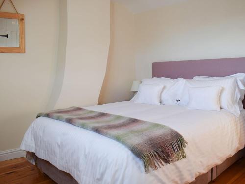 ein Schlafzimmer mit einem weißen Bett und einer gestreiften Decke in der Unterkunft Rowan Cottage in Aislaby