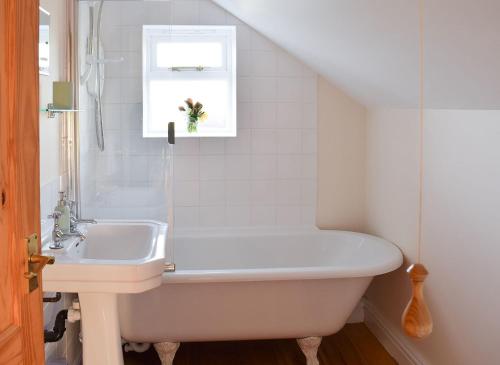a bathroom with a bath tub and a sink at Rowan Cottage in Aislaby