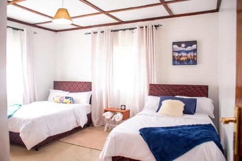 1 Schlafzimmer mit 2 Betten und einem Fenster in der Unterkunft The Nest Airbnb - Milimani, Kitale in Kitale