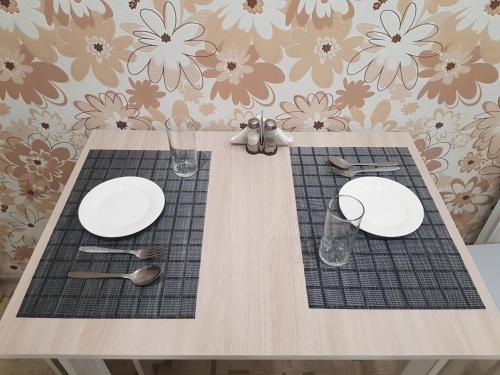 una mesa con dos platos blancos y cubiertos en квартира en Pavlodar