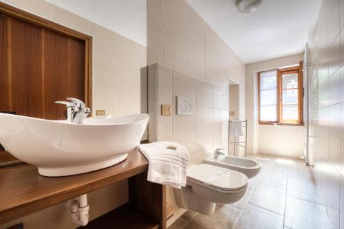 La salle de bains blanche est pourvue d'un lavabo et de toilettes. dans l'établissement Incanto Walser Apartments Piazza, à Macugnaga