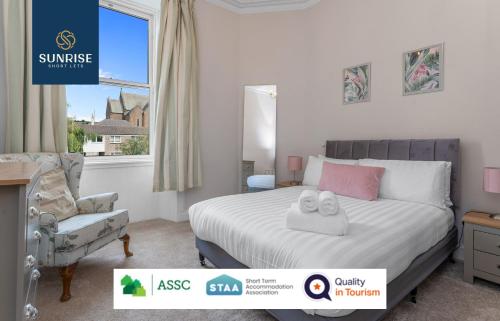 a bedroom with a bed and a chair and a window at DUPLEX - INVOICE and REDUCED PRICE only via SUNRISE SHORT LETS DUNDEE, 5 Bed Rooms, Amazing Views, Fully Equipped, Free Parking, WiFi, FAVOURITE for Groups & Businesses, Food, Bars, Shops, Library, River Views, and ONLY 5 Mins to STANNERGATE Ports in Dundee