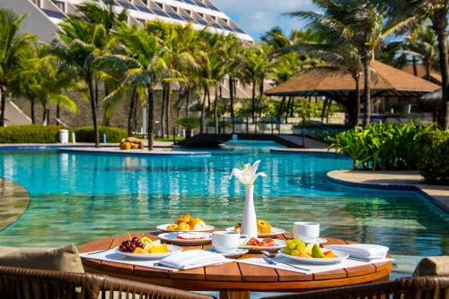 a table with food on it next to a swimming pool at Wish Natal in Natal
