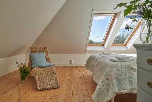 a bedroom with a bed and a chair and a window at Red Haven Cottage in Edsbruk
