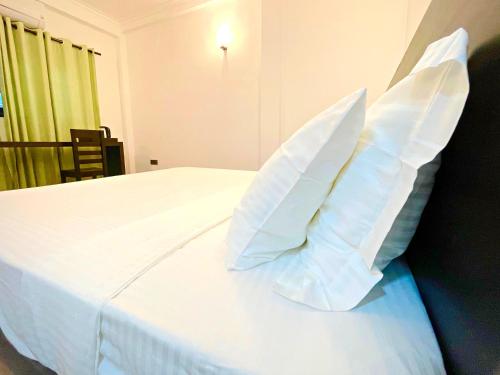 ein weißes Bett mit weißen Kissen darüber in der Unterkunft The Ivy Lake in Anuradhapura