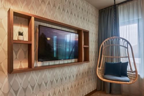 a hanging chair with a television in a room at Cocoon Salzburg in Salzburg