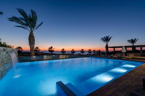 a swimming pool with a sunset in the background at Beachfront Luxury Villa Glory in Ayia Napa