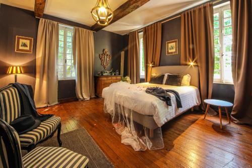 a bedroom with a bed and a chair at Le Manoir du Thouron in Saint-Sulpice