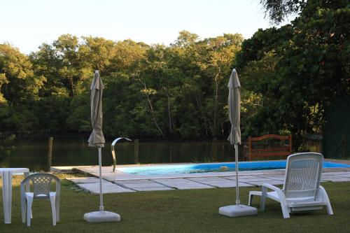 2 sillas y sombrillas frente a una piscina en Pousada Joaripe en Nova Almeida