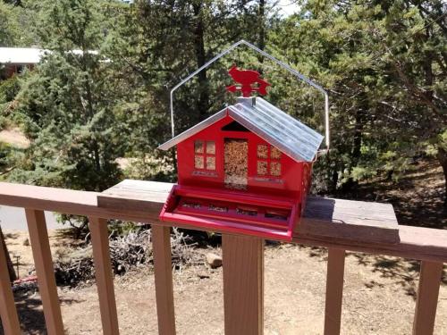 a red bird house on top of a wooden rail at Historical Cabin in Julian Pet's okay! in Julian