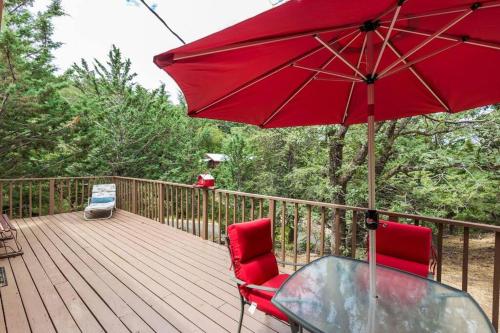 a wooden deck with a glass table and a red umbrella at Historical Cabin in Julian Pet's okay! in Julian