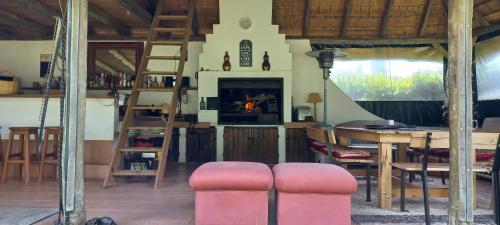 a living room with a fireplace and a table and chairs at Rosedale Self Catering Cottage with pool and large entertainment BBQ area in Henburg Park