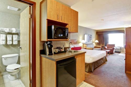 a hotel room with a bed and a bathroom at Ramada by Wyndham Ponoka in Ponoka