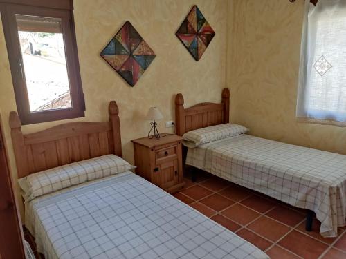 two beds in a room with two windows at Casa Rural La Torreta en El Rincón de Ademuz in Castielfabib