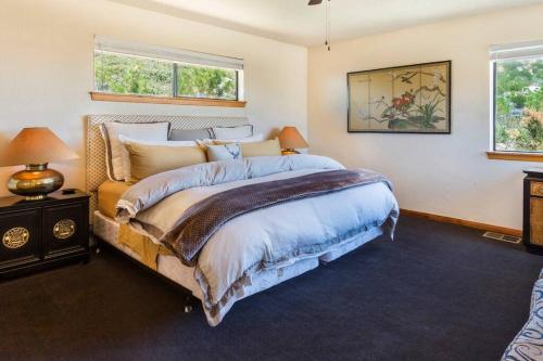 a bedroom with a large bed and two windows at A LIVING CANVAS Amazing Lake View Custom Home in Julian