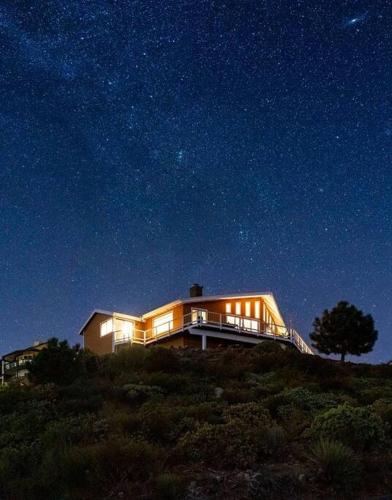 a house sitting on top of a hill at night at A LIVING CANVAS Amazing Lake View Custom Home in Julian