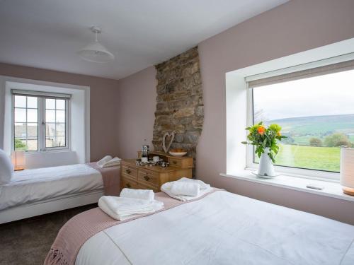 Lyndhurst Cottage في كارلتون: غرفة نوم بسريرين ونافذة بها ورد