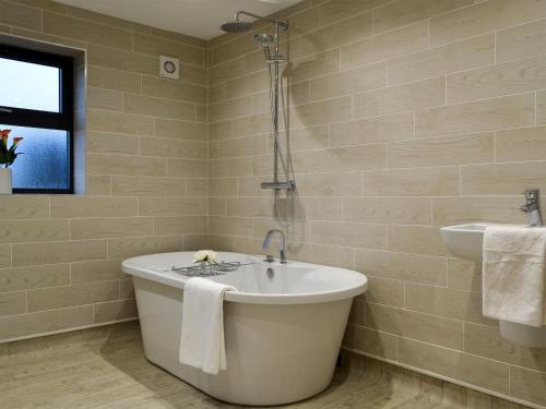 ein Badezimmer mit einer Badewanne und einem Waschbecken in der Unterkunft North Plain Barn in Bowness-on-Solway