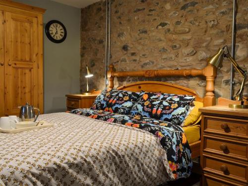 ein Schlafzimmer mit einem Bett und einer Uhr an der Wand in der Unterkunft North Plain Barn in Bowness-on-Solway