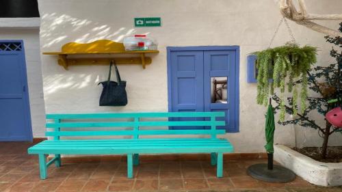 un banc bleu devant un bâtiment avec une porte bleue dans l'établissement Tree of Life - Hostel, à Barichara