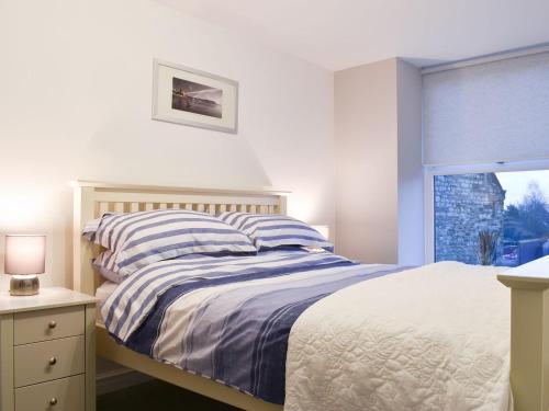 ein weißes Schlafzimmer mit einem Bett und einem Fenster in der Unterkunft Millys Cottage in Ayton