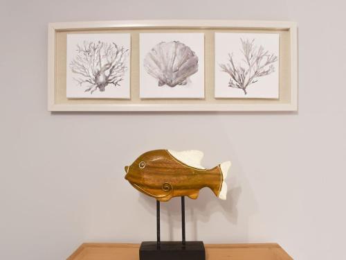 una escultura de pescado en una mesa delante de tres fotos en Millys Cottage, en Ayton