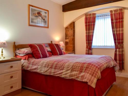 a bedroom with a bed with red pillows and a window at The Coach House - UK30397 in Calvo