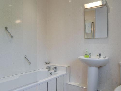 uma casa de banho com um lavatório e uma banheira e um lavatório em Ribblestones em Austwick