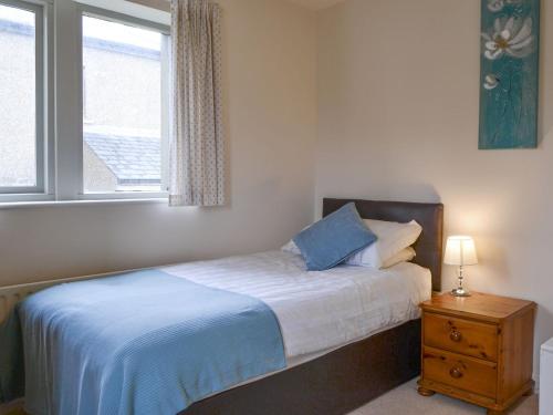 a bedroom with a bed and a window and a nightstand at Ribblestones in Austwick