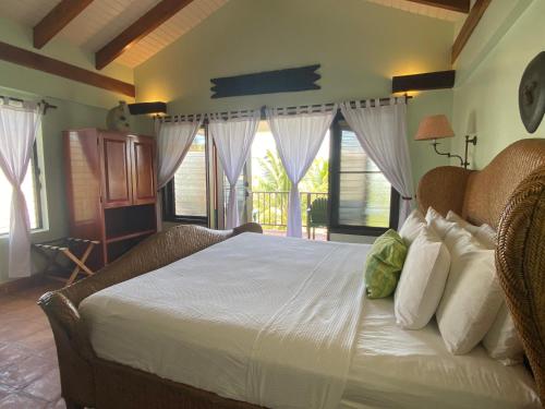 a bedroom with a bed with white sheets and windows at Tranquility Beach Suites in Placencia