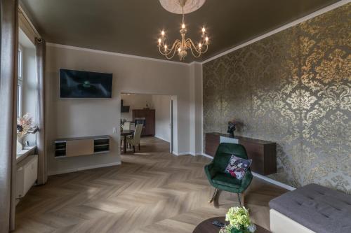 een woonkamer met een groene stoel en een kroonluchter bij Ferienappartements-Milina in Rathmannsdorf