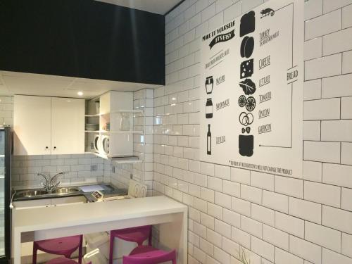 una cocina con taburetes rosas y una pared de azulejos blancos en Chameleon Youth Hostel Alicante, en Alicante