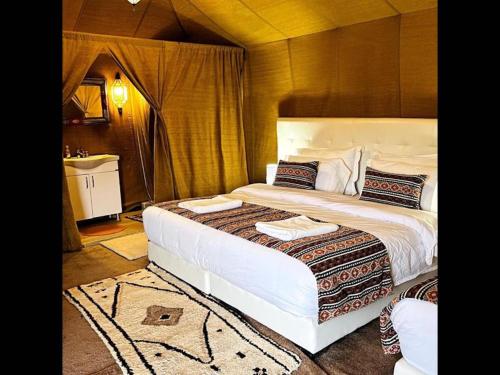 1 dormitorio con 1 cama grande y lavamanos en Room in Bungalow - Saharian Luxury Camp, en Tisserdmine