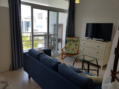 a living room with a blue couch and a tv at Seaview Modern Studio in Sihanoukville