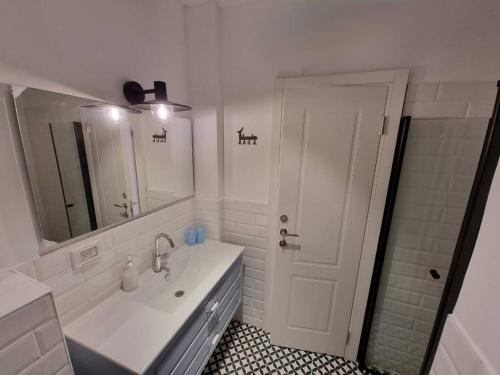 W białej łazience znajduje się umywalka i lustro. w obiekcie Beautiful 2-Bedroom Sea-View apartment w mieście Netanja