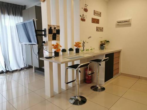 a kitchen with a desk with stools and a television at Eko Studio@EVO SOHO BANGI with NETFLIX & WIFI in Kampong Sungai Ramal Dalam