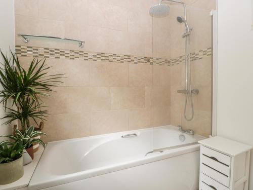 a white bath tub in a bathroom with a plant at Highbank in Wareham