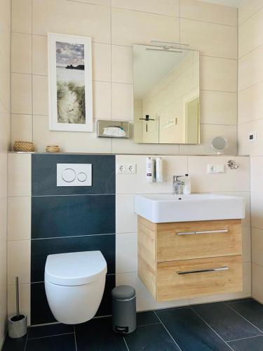 a bathroom with a toilet and a sink and a mirror at Dünenhaus Ferienwohnung De Düün Een in Wangerooge