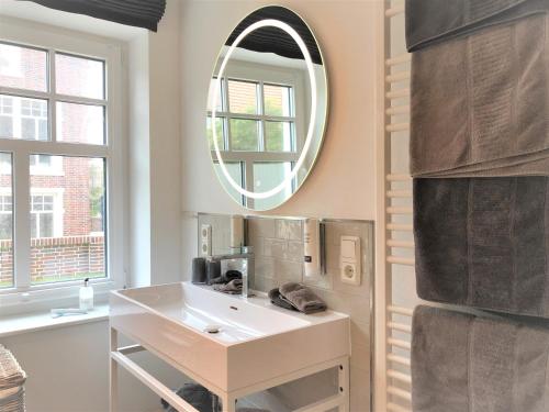 uma casa de banho com um lavatório branco e um espelho. em Ferienwohnung Strandmuschel em Wangerooge