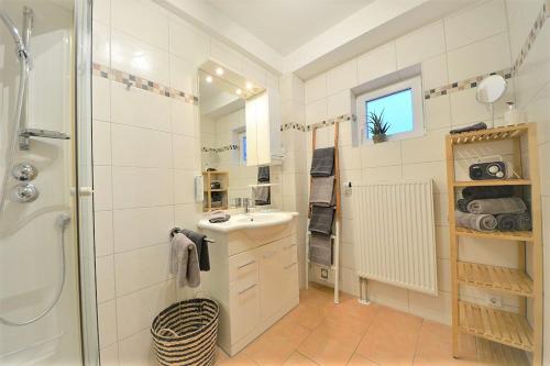 La salle de bains blanche est pourvue d'un lavabo et d'une douche. dans l'établissement Ferienwohnung Auszeit, à Wangerooge