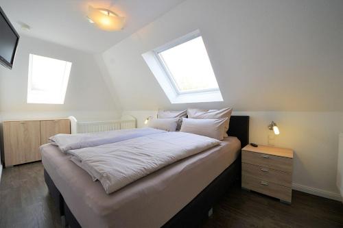 um quarto com uma cama grande e 2 janelas em Ferienwohnung Kellingooge em Wangerooge