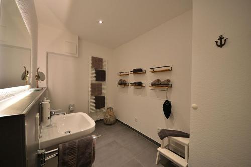 La salle de bains blanche est pourvue d'un lavabo et d'un miroir. dans l'établissement Ferienwohnung STRAND PIET, à Wangerooge