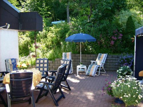 a patio with chairs and a table and an umbrella at Gästehaus Hochrhönblick in Schönau an der Brend