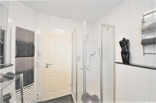 een witte badkamer met een douche en een glazen deur bij Villa Vivaldi - Ferienwohnung 3 in Wangerooge