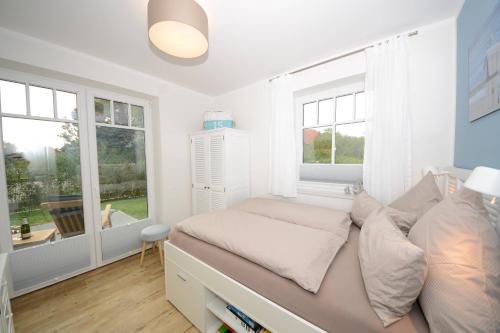 a bedroom with a bed and two windows at Ferienwohnung Strandbude in Wangerooge
