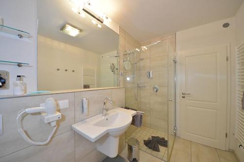 La salle de bains blanche est pourvue d'un lavabo et d'une douche. dans l'établissement Villa Verdi - Ferienwohnung 2, à Wangerooge