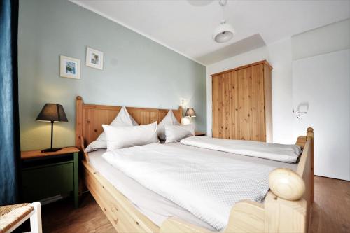 um quarto com uma grande cama branca e uma cabeceira em madeira em Haus Blümlein Wangerooge em Wangerooge